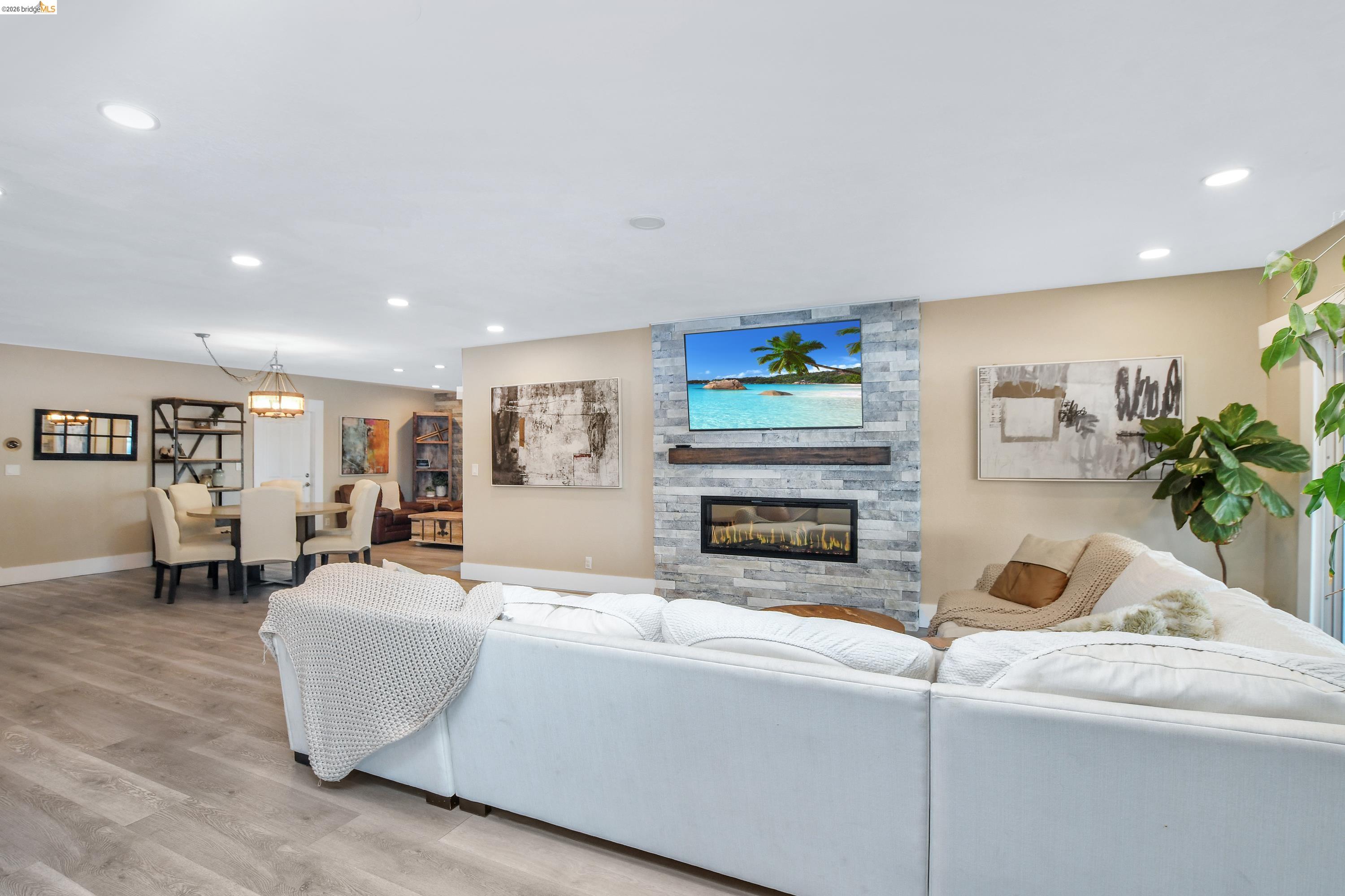 1432 Willow Lake Road Discovery Bay, CA 94505 - Photo 10 of 40 Open-concept living area featuring wood-finish flooring, recessed lighting, and a stacked stone accent wall with a built-in fireplace