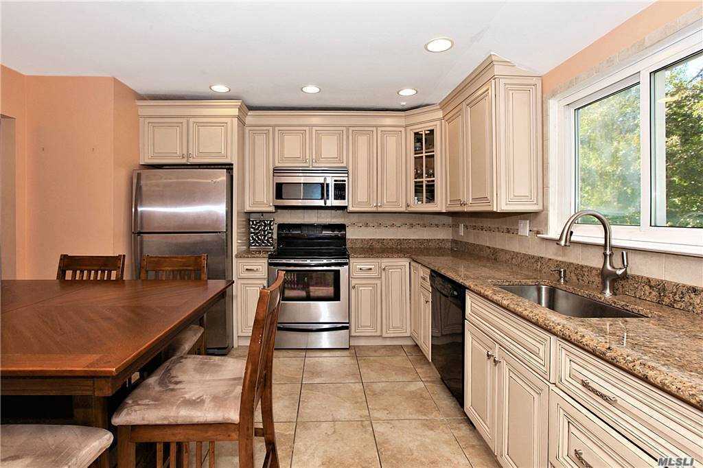 a kitchen with kitchen island granite countertop a sink appliances cabinets and counter space