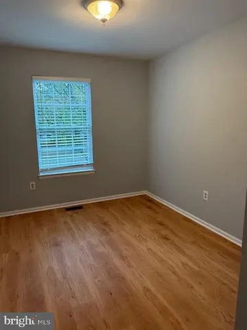 an empty room with wooden floor and natural light