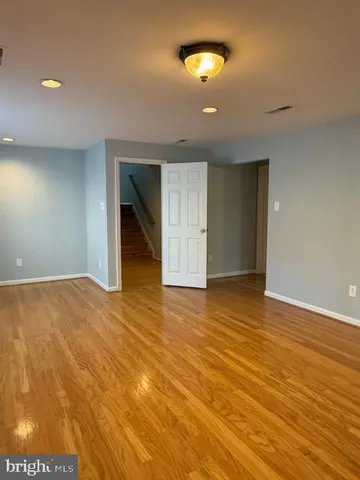 a view of an empty room with window and chandelier fan