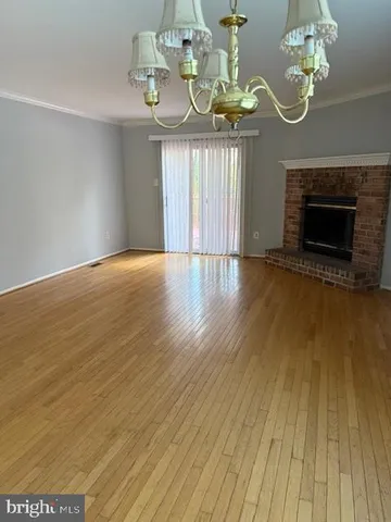 a view of wooden floor a chandelier and a fireplace in room