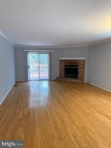 an empty room with wooden floor fireplace and windows