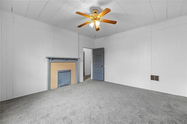 a view of an empty room with a ceiling fan and a fireplace