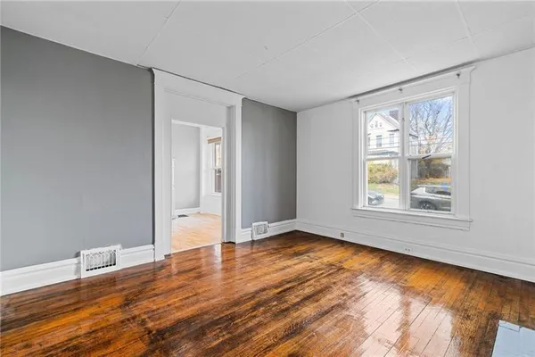 a view of an empty room with wooden floor and a window
