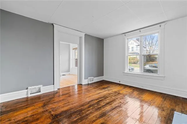 a view of an empty room with wooden floor and a window