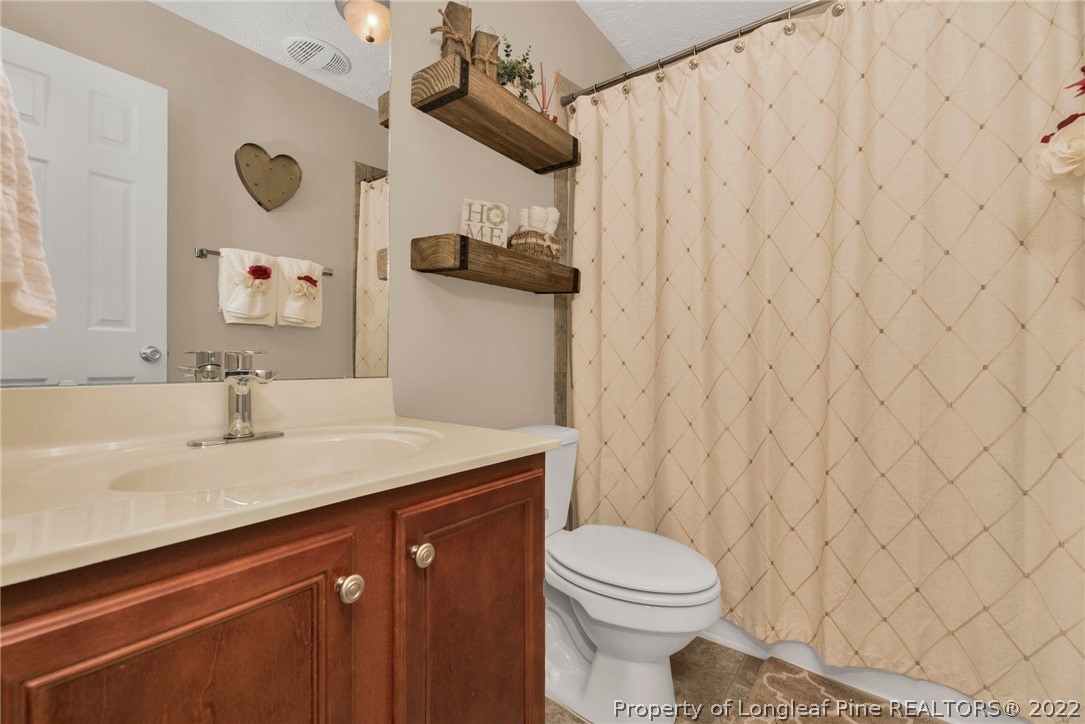 723 Cape Fear Road Raeford, NC 28376 - Photo 22 of 33 a bathroom with a granite countertop sink mirror vanity and toilet
