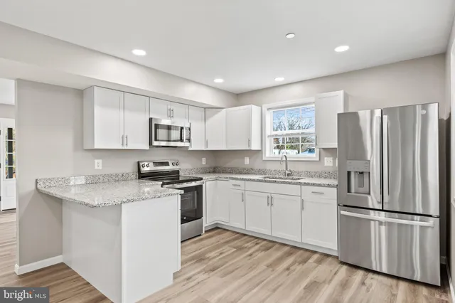 a kitchen with granite countertop stainless steel appliances a refrigerator sink and microwave