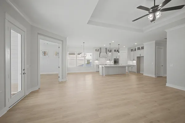 a large white kitchen with a stove a sink dishwasher a refrigerator and a fireplace with wooden floor