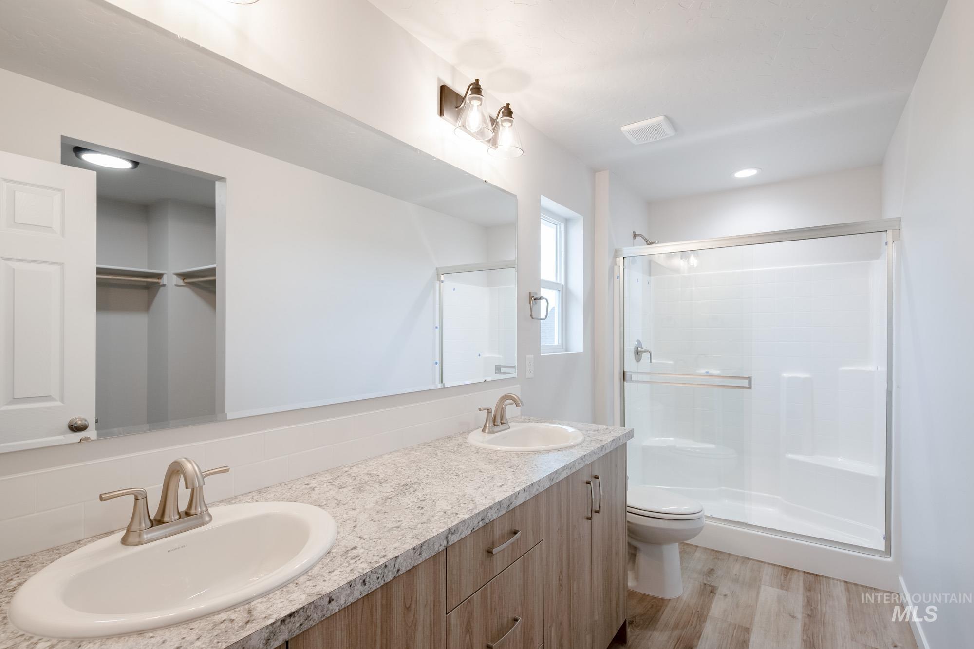 1711 North Birch Street Jerome, ID 83338 - Photo 10 of 16 Full bath with double vanity, a stall shower, light wood-type flooring, and a walk in closet