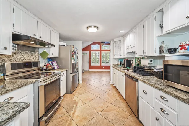 a large kitchen with stainless steel appliances granite countertop a stove a sink and a refrigerator