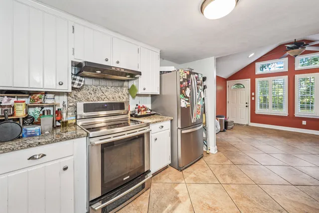 a kitchen with stainless steel appliances granite countertop a stove a refrigerator and a white cabinets