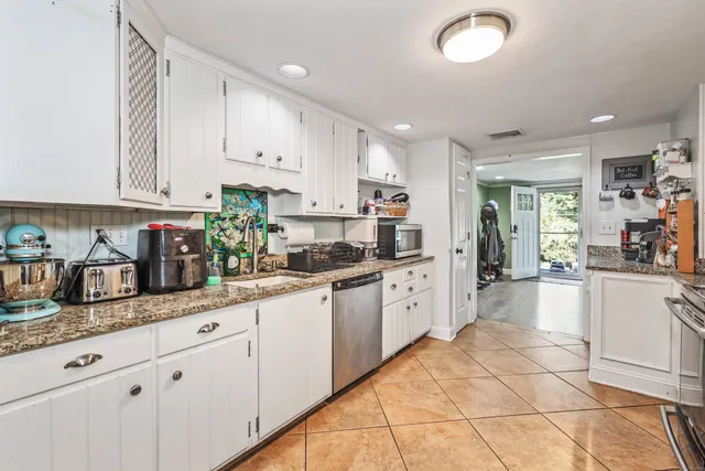 a kitchen with granite countertop white cabinets white appliances a sink and a counter space