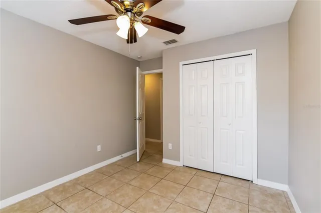 an empty room with closet and a chandelier fan