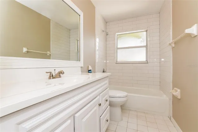 a bathroom with a granite countertop sink a toilet a mirror and a bathtub