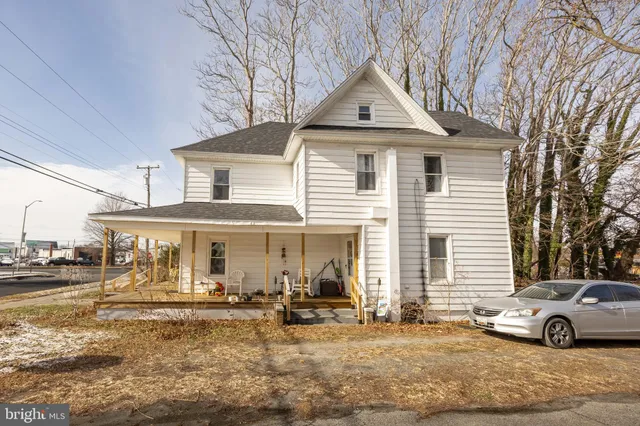 a view of a white house with couches next to a yard