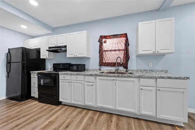 a kitchen with granite countertop white cabinets and stainless steel appliances
