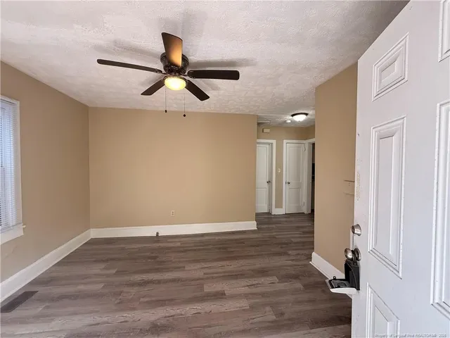 a view of empty room with wooden floor and fan