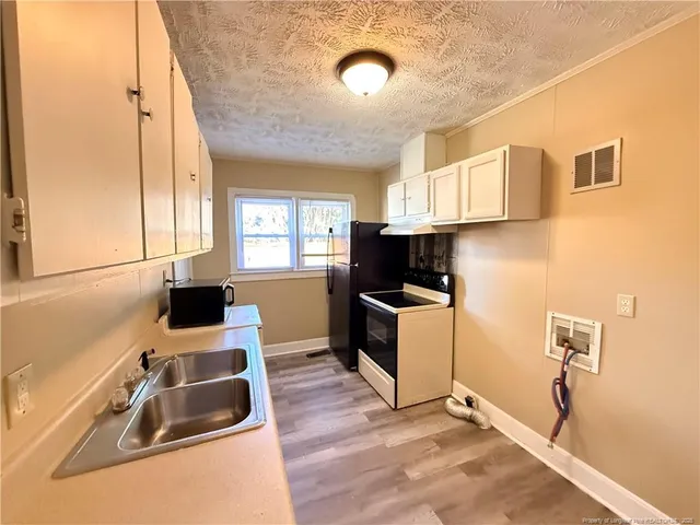a kitchen with granite countertop a sink a counter top space and cabinets
