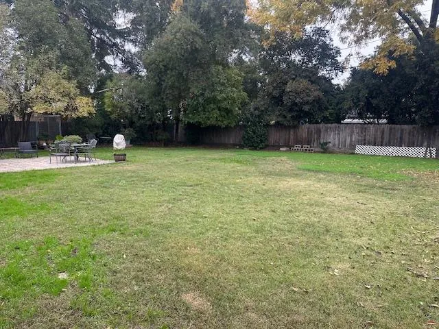 a view of a backyard with table and chairs a barbeque and a large trees