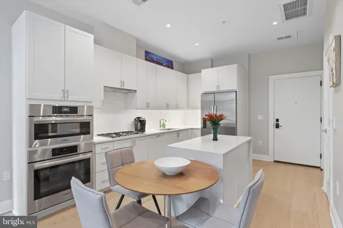 a kitchen with stainless steel appliances kitchen island granite countertop a sink a stove a table and chairs