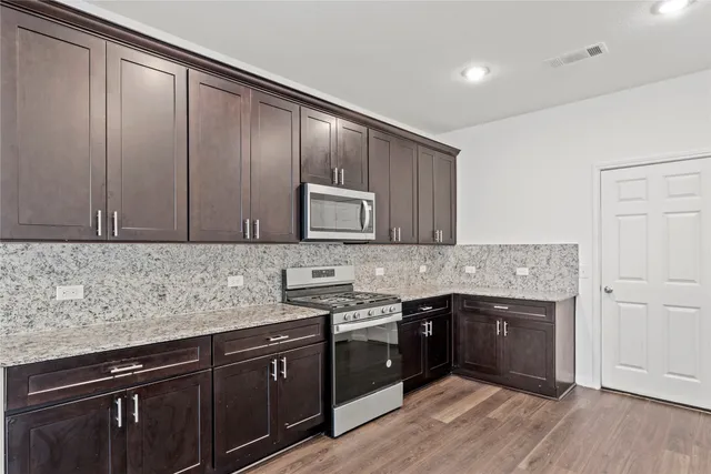 a kitchen with stainless steel appliances granite countertop a sink stove and cabinets