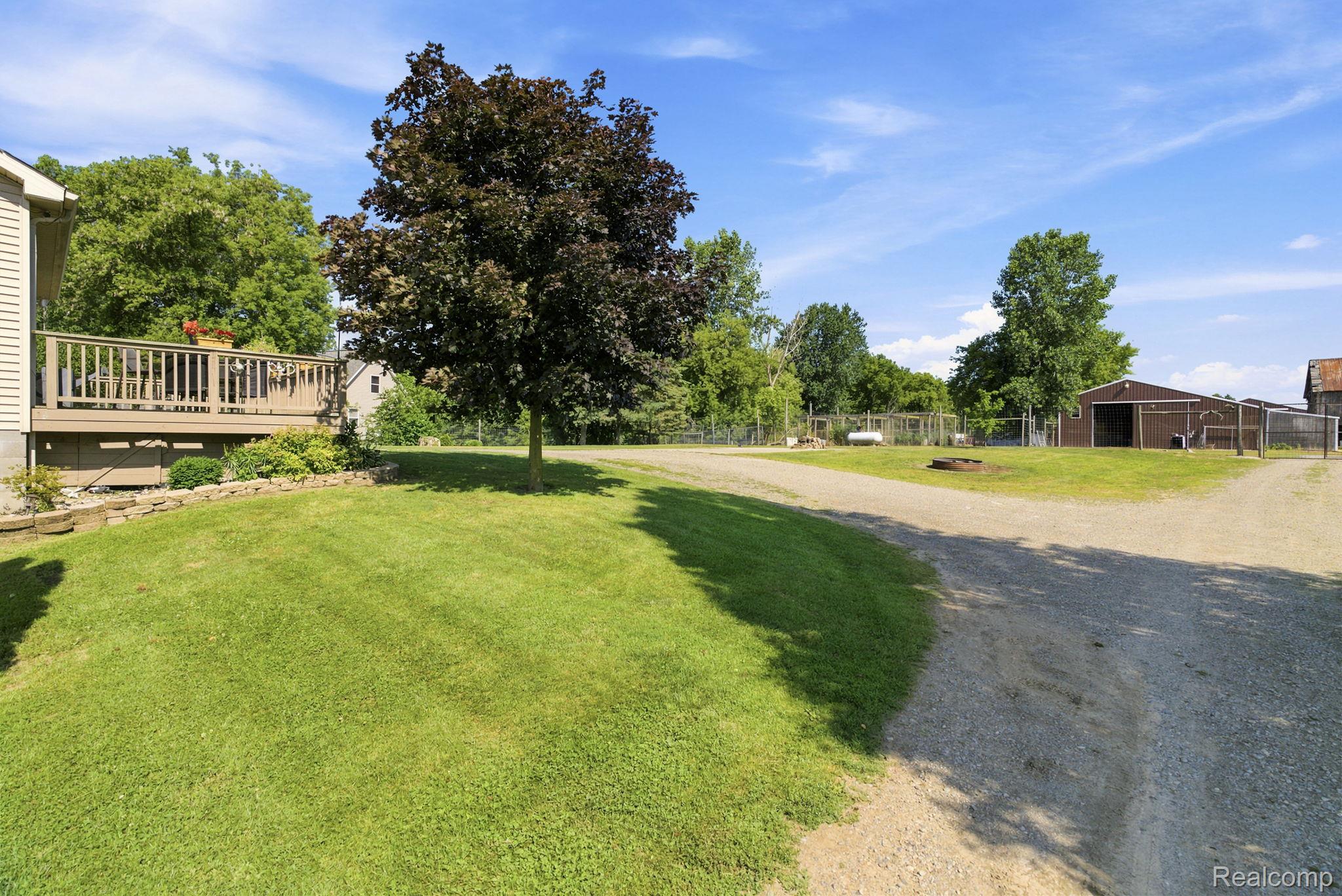 4201 Galbraith Line Road Croswell, MI 48422 - Photo 30 of 39 Expansive outdoor space featuring a wide gravel driveway, mature trees, and a detached barn structure