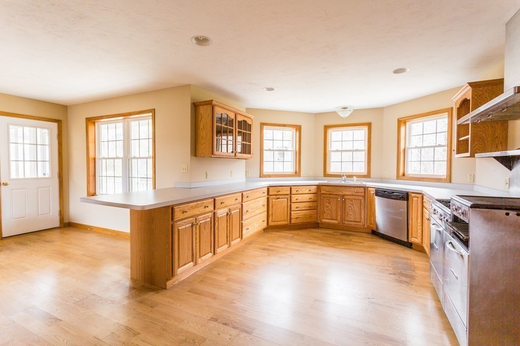 147 Ragged Hill Road West Brookfield, MA 01585 - Photo 5 of 42 a large kitchen with stainless steel appliances granite countertop a large stove a sink dishwasher and white cabinets with wooden floor
