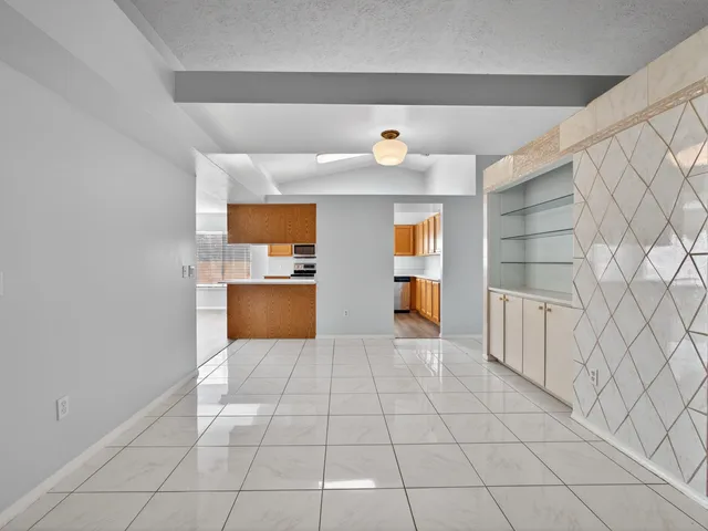a view of a livingroom with wooden floor a ceiling fan and windows