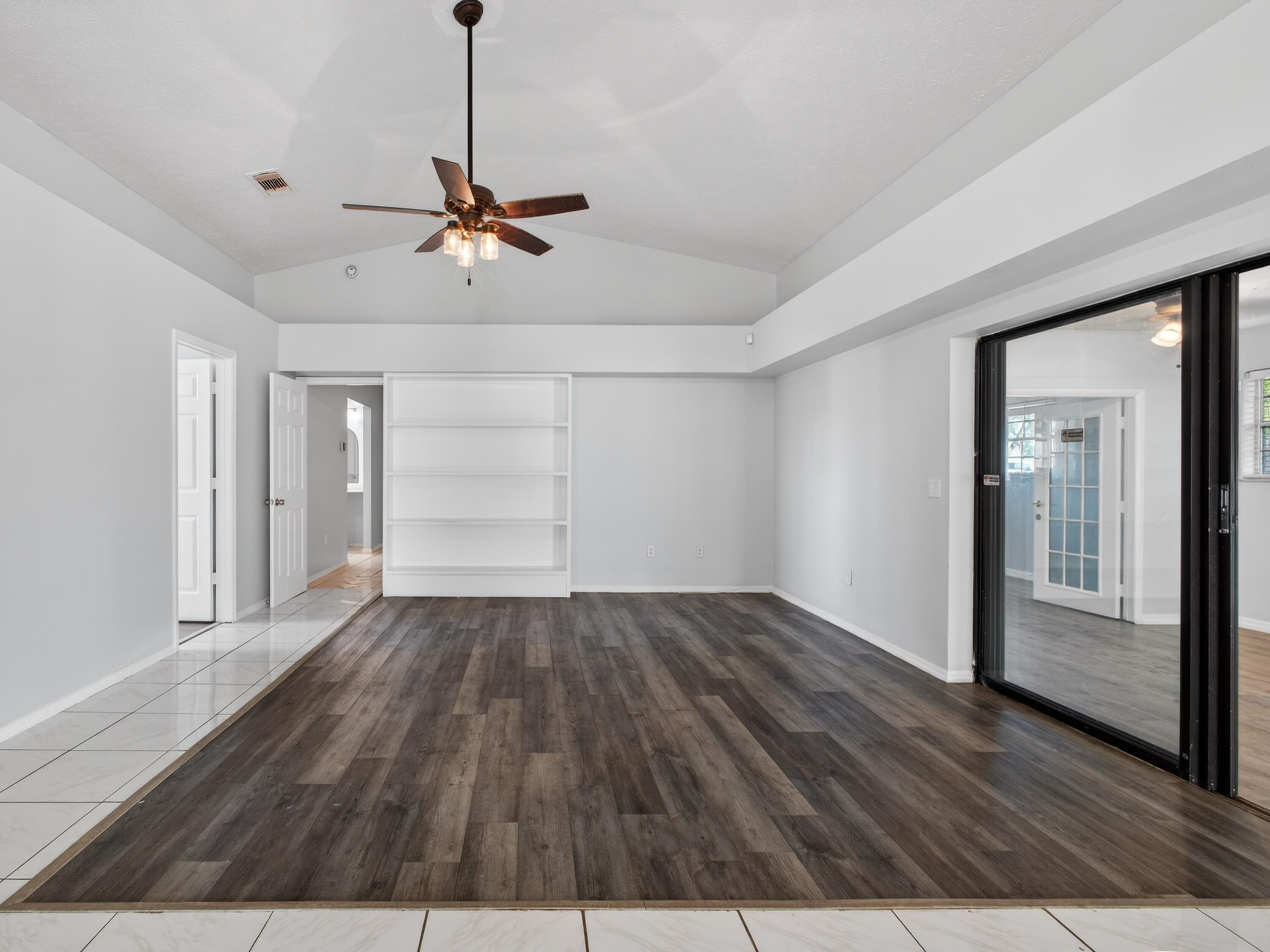 566 Southeast Damask Avenue Port St. Lucie, FL 34983 - Photo 14 of 30 a view of a livingroom with wooden floor a ceiling fan and windows