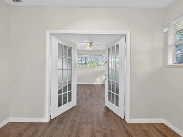 a view of an empty room with a window and wooden floor