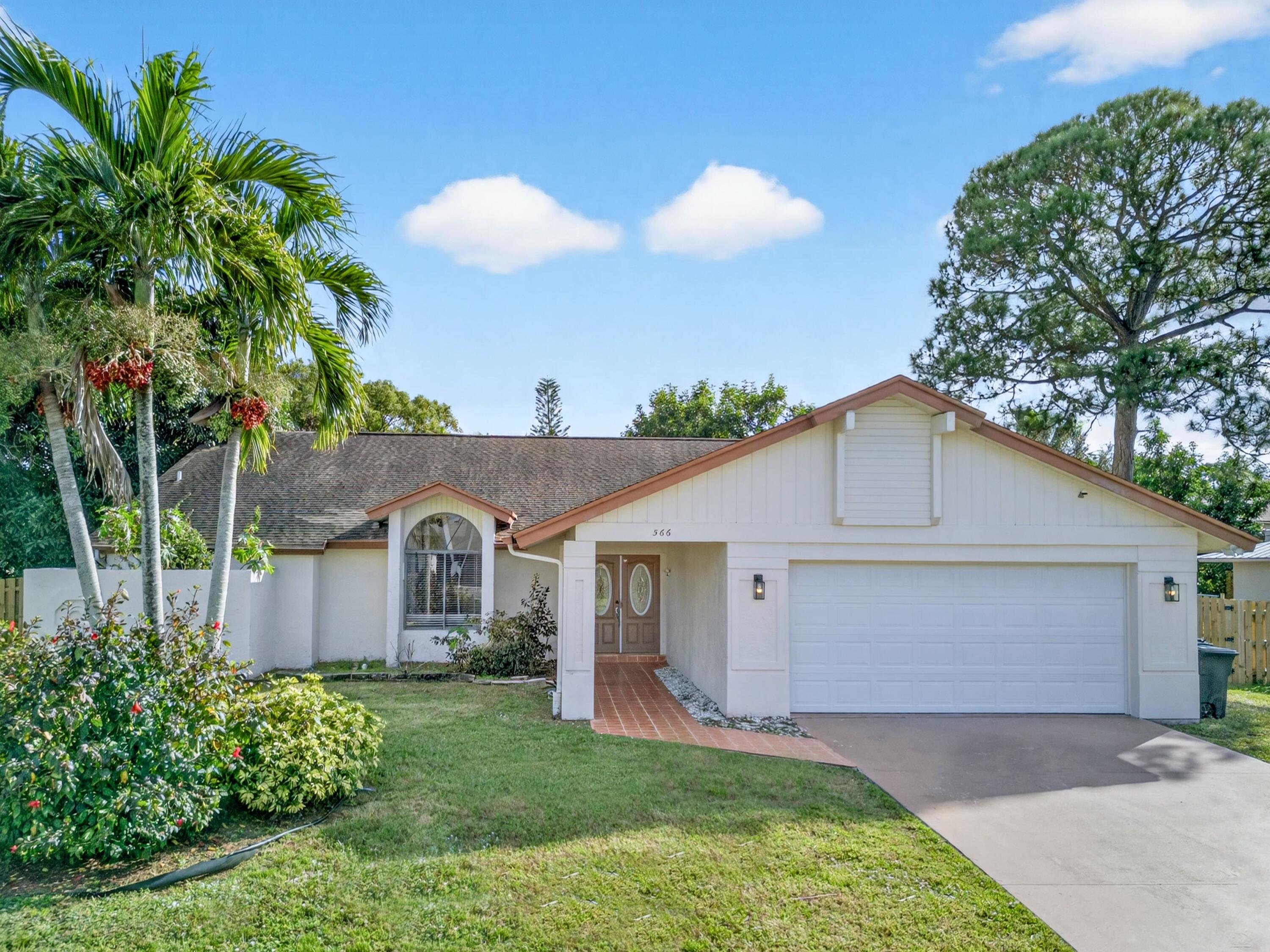566 Southeast Damask Avenue Port St. Lucie, FL 34983 - Photo 3 of 30 a front view of a house with a yard and garage