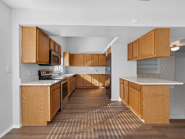 a kitchen with stainless steel appliances granite countertop a refrigerator a stove a sink and dishwasher with wooden floor