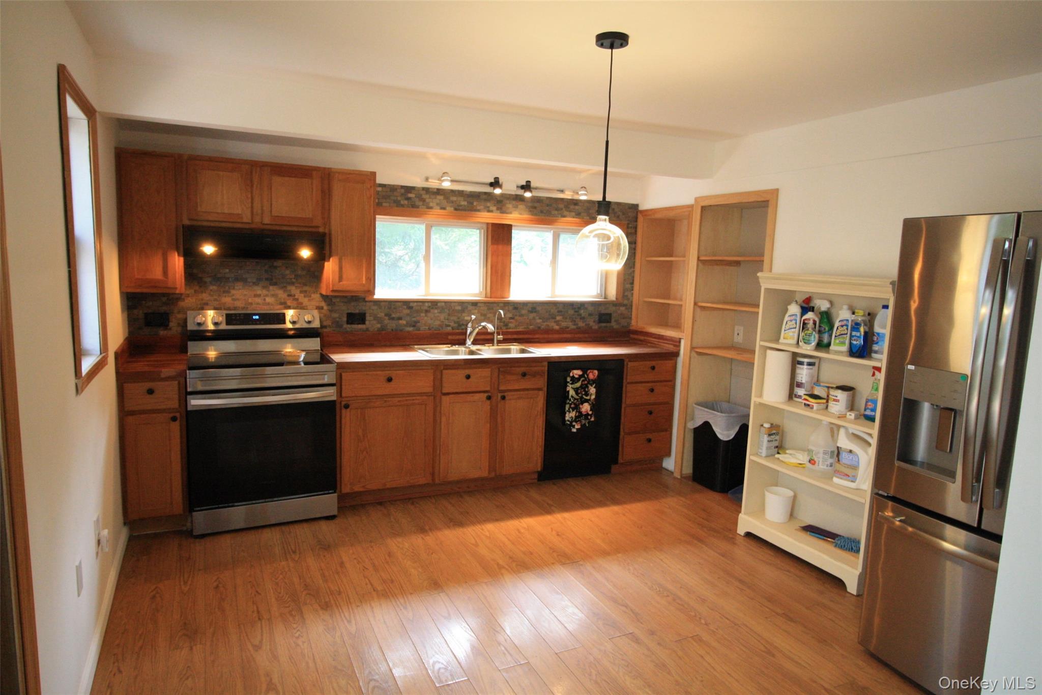 50 Mt Hope Road Carmel, NY 10512 - Photo 6 of 13 Kitchen with appliances with stainless steel finishes, brown cabinets, decorative backsplash, and decorative light fixtures