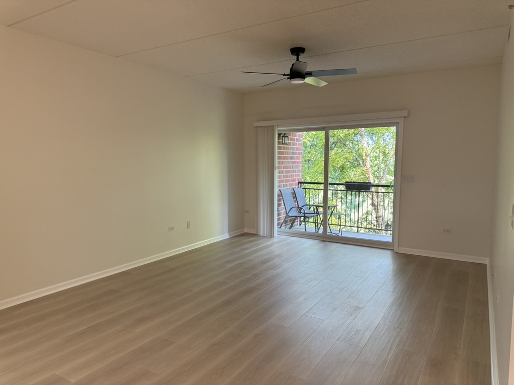 3401 North Carriageway Drive, Unit 307 Arlington Heights, IL 60004 - Photo 2 of 11 an empty room with wooden floor fan and windows
