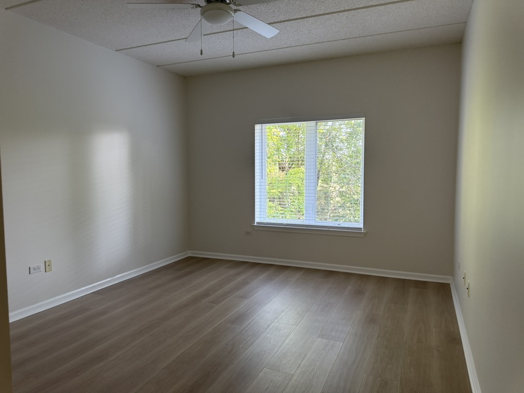 3401 North Carriageway Drive, Unit 307 Arlington Heights, IL 60004 - Photo 6 of 11 an empty room with wooden floor and windows