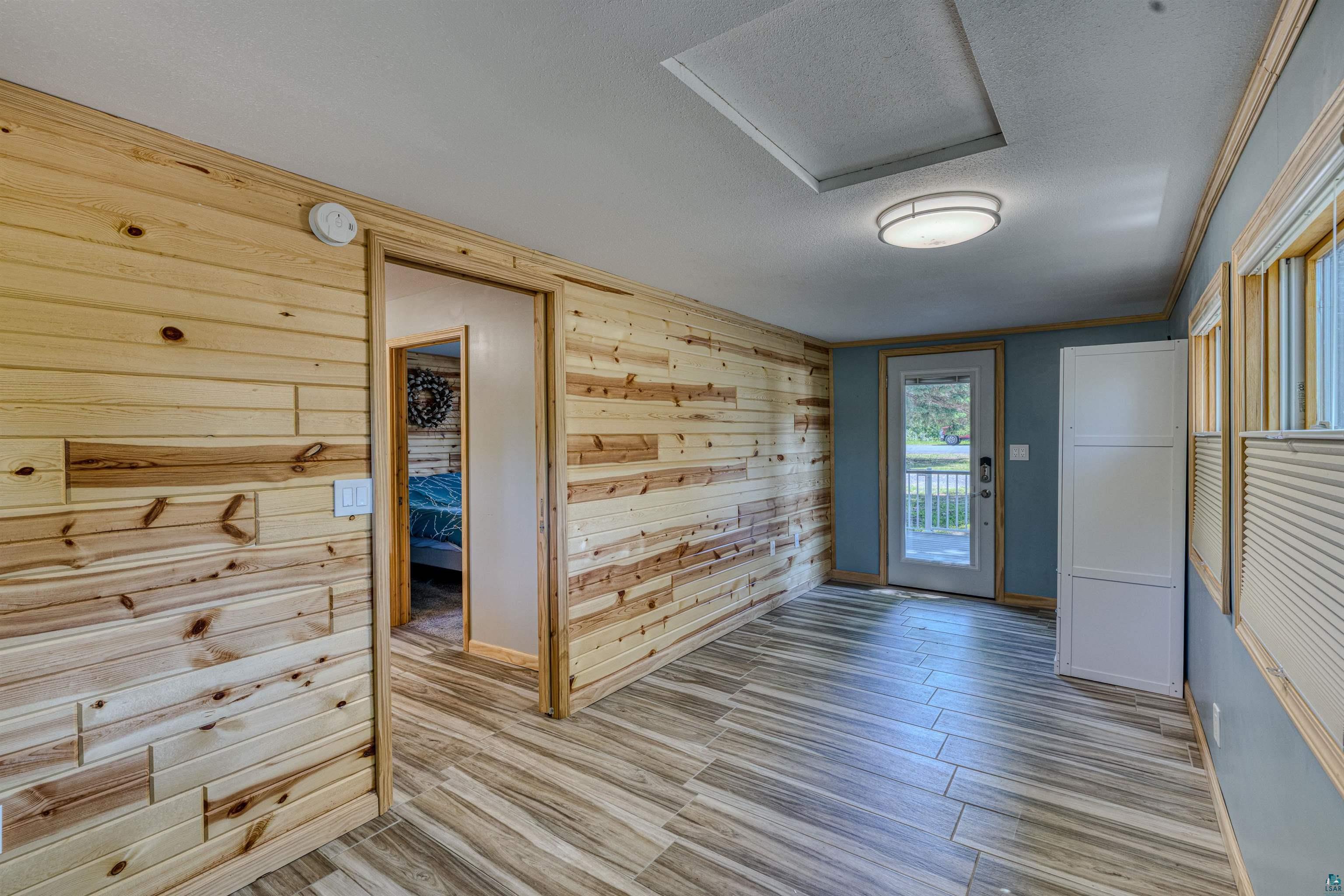 66075 Rooster Road Iron River, WI 54847 - Photo 23 of 52 Room featuring wood-finish plank accent walls and wood-look tile flooring
