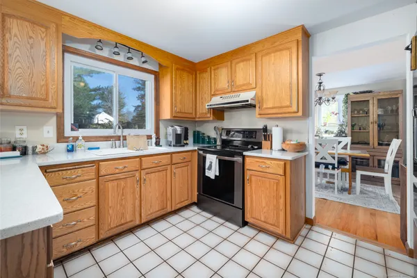 a kitchen with stainless steel appliances granite countertop a stove top oven a sink a dining table and chairs