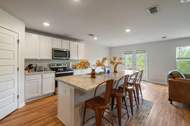 a kitchen with stainless steel appliances granite countertop a table chairs refrigerator and microwave