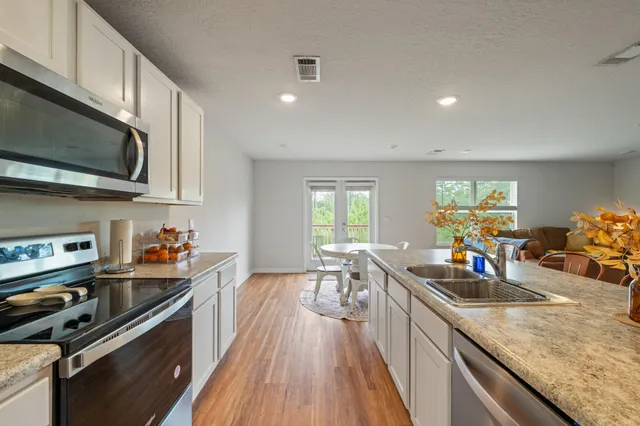 a kitchen view with wooden floor a stove and a sink