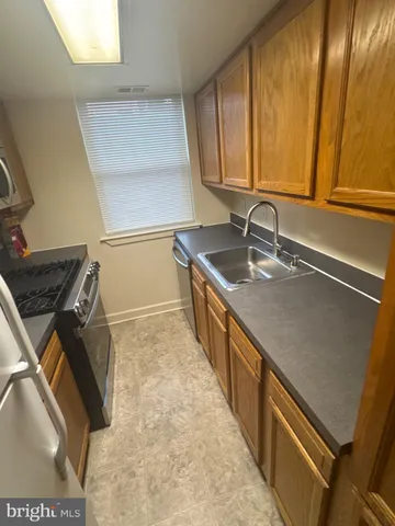 a kitchen with granite countertop a sink a stove and refrigerator