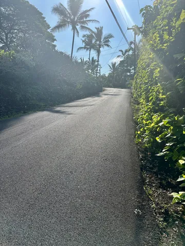 a view of a rural road with a house in the background