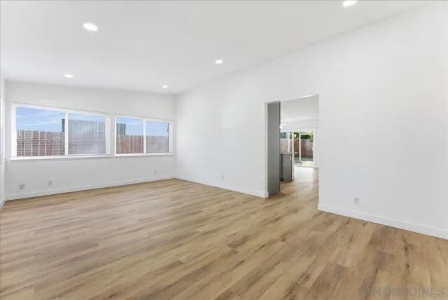 a view of empty room with wooden floor and windows
