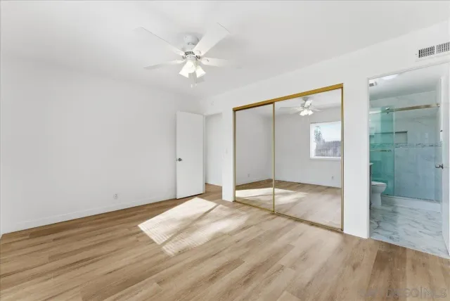 a view of an empty room with wooden floor and mirror