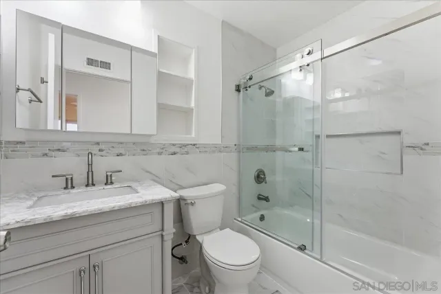 a bathroom with a shower sink vanity mirror and toilet