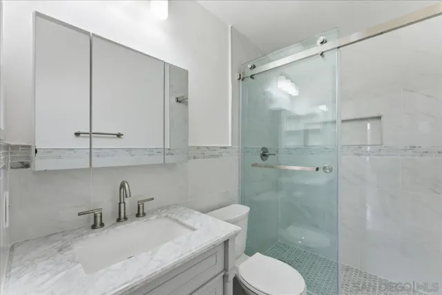 a bathroom with a granite countertop sink toilet a mirror and shower