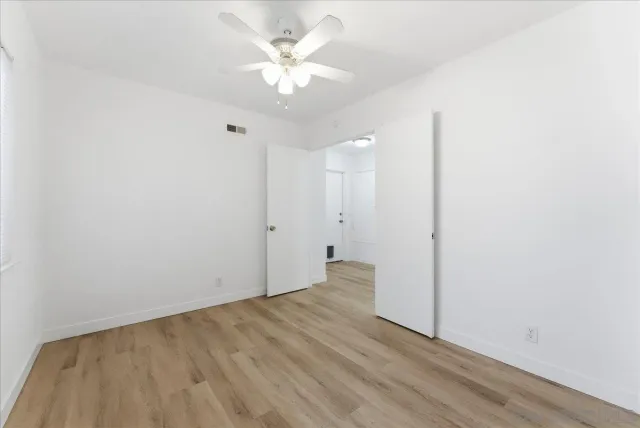 an empty room with a white cabinet and a ceiling fan