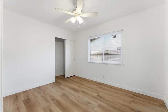 an empty room with a window and a ceiling fan