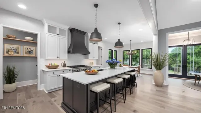 a open kitchen with stainless steel appliances granite countertop a stove top oven a dining table and chairs with wooden floor