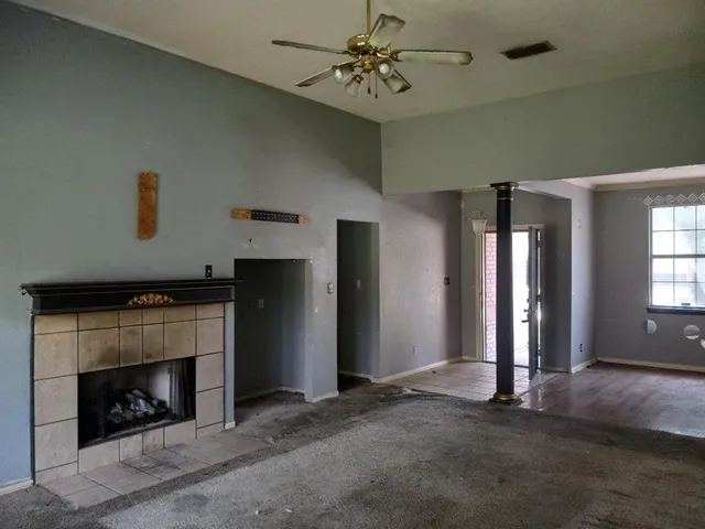 an empty room with windows and fireplace