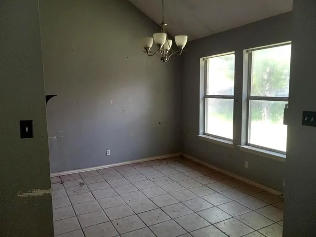 en empty room with windows and chandelier